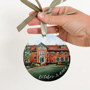 May include: A round, painted bauble depicting a brick building with a green lawn and trees. The bauble is decorated with the date "October 5, 2024" in white calligraphy.