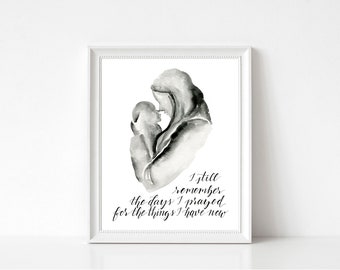 May include: Black and white watercolour illustration of a mother holding a child. The text reads "I still remember the days I prayed for the things I have now."