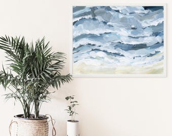 May include: Abstract painting of blue and white waves in a white frame. The painting is hanging on a white wall with a potted plant in front of it.