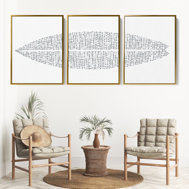 May include: Three framed abstract art prints with a white background and a pattern of small gray dots arranged in a wave-like design. The frames are gold.