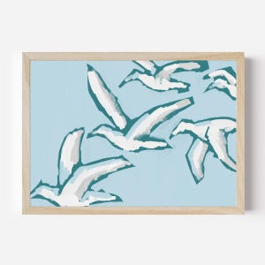 May include: A framed print of a minimalist abstract painting featuring white birds flying against a light blue background. The birds are painted in a simple, stylized manner, with their wings outstretched and their bodies outlined in a dark teal color.
