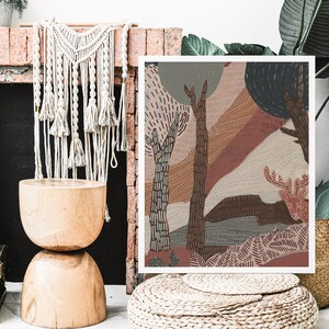 May include: Abstract art print featuring a stylized forest scene with trees, foliage, and a deer in shades of brown, pink, and blue. The print is framed and hanging on a wall.