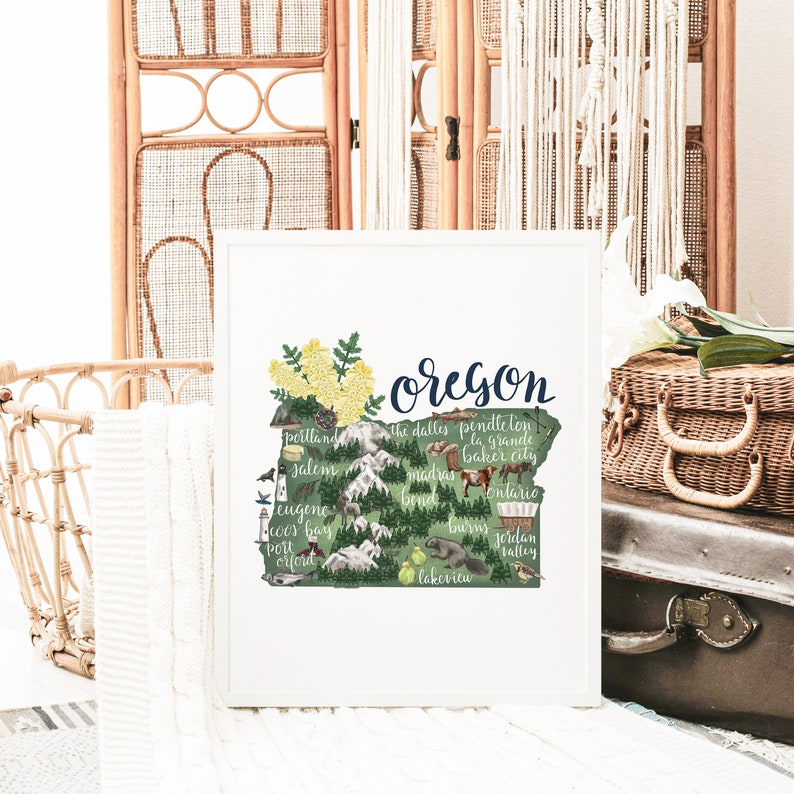 May include: A green and white illustrated map of Oregon with the state name written in blue cursive. The map includes the names of major cities and towns throughout the state, including Portland, Salem, Eugene, and Bend.