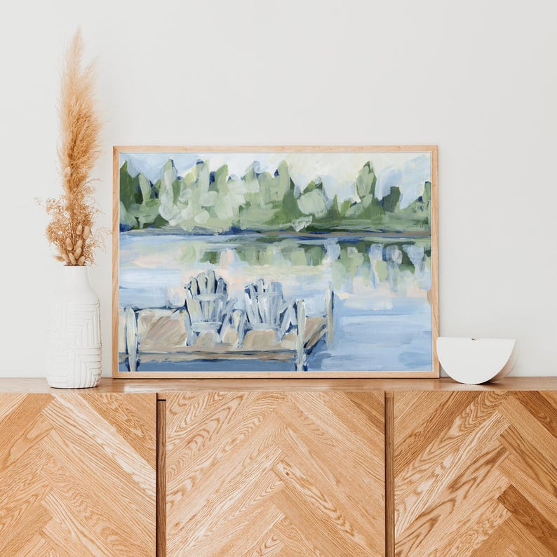 Pode incluir: Uma pintura de uma cena de lago com duas cadeiras em um cais. O lago &eacute; azul e as &aacute;rvores s&atilde;o verdes. As cadeiras s&atilde;o brancas e azuis.