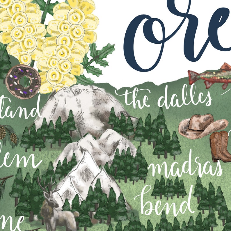 May include: A watercolor illustration of the state of Oregon with the word "Oregon" in navy blue script at the top. The illustration features a variety of iconic landmarks and symbols of the state, including mountains, forests, a donut, a fish, a cowboy hat, and a deer. The names of several cities in Oregon are also included in the illustration, including "The Dalles", "Madras", and "Bend".