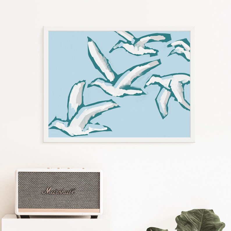 May include: A framed print of a minimalist abstract art design featuring white birds flying against a light blue background. The birds are outlined in teal.