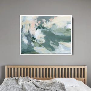 May include: Abstract art print in a white frame. The artwork features brushstrokes of teal, white, and pale pink. The painting has a modern, minimalist style, suitable for home decor. The canvas is mounted above a wooden bed frame.