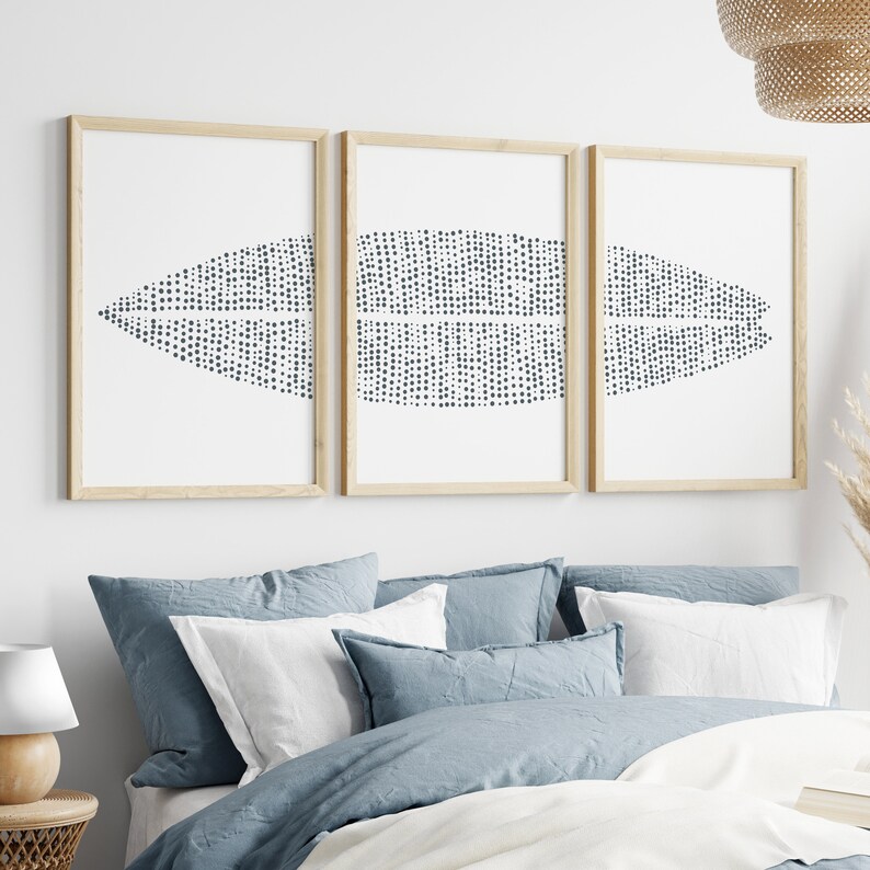 May include: Three framed prints with a white background and a black and white abstract design of a dotted leaf shape. The frames are natural wood.