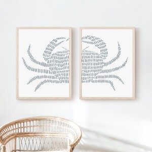 May include: Two framed prints of a stylized crab design in blue on a white background. The crab is made up of a series of vertical lines.