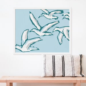 May include: A framed print of a minimalist abstract art design featuring white birds flying in a teal blue sky.
