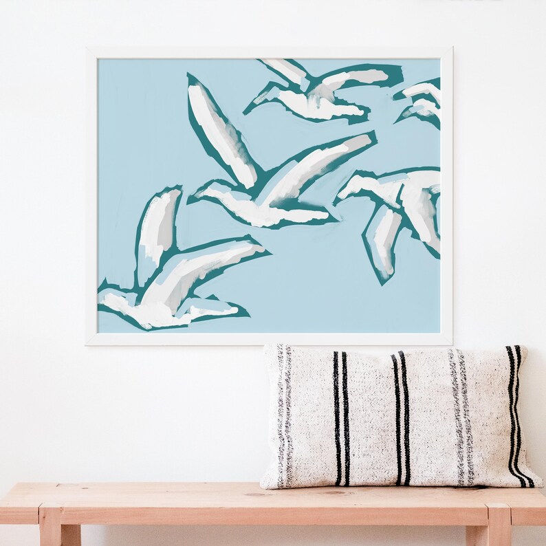 May include: A framed print of a minimalist abstract art design featuring white birds flying in a teal blue sky.