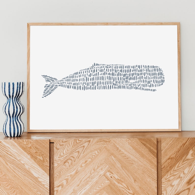 May include: A framed print of a stylized whale illustration in shades of blue against a white background. The whale is made up of a series of short, vertical lines.