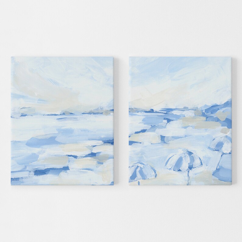 May include: A set of two abstract paintings on canvas. The paintings are in shades of blue and white and depict a seascape with a horizon line and clouds. The right painting also features a few white umbrellas.