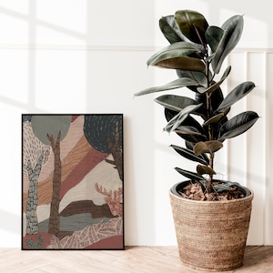 May include: A framed abstract art print with a brown, orange, and blue color scheme depicting a stylized forest scene. The print is hanging on a white wall next to a potted ficus plant with dark green leaves.