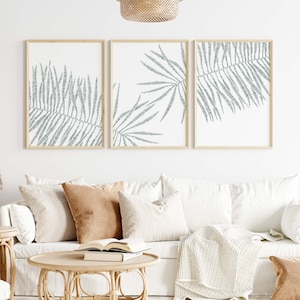 May include: Three framed prints with a minimalist design featuring a stylized outline of palm leaves in a muted teal color.