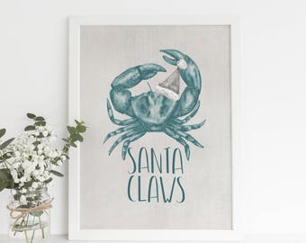 May include: A framed print featuring a teal crab wearing a Santa hat. The words "SANTA CLAWS" are written in teal script below the crab. The artwork is displayed in a white frame.