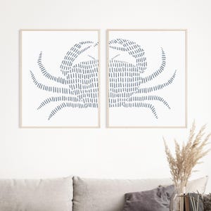 May include: Two framed prints of a stylized crab design in a dark blue color on a white background.