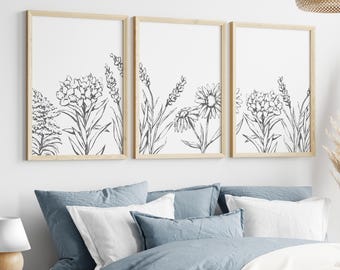 May include: Three framed black and white line drawings of flowers and foliage. The frames are light wood and the drawings are arranged in a row.