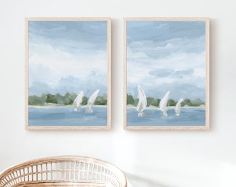 May include: Two framed paintings of a seascape with sailboats. The paintings are in a light blue and white color scheme and feature a light blue sky with white clouds and a light blue ocean with white sailboats. The paintings are framed in a light wood frame.