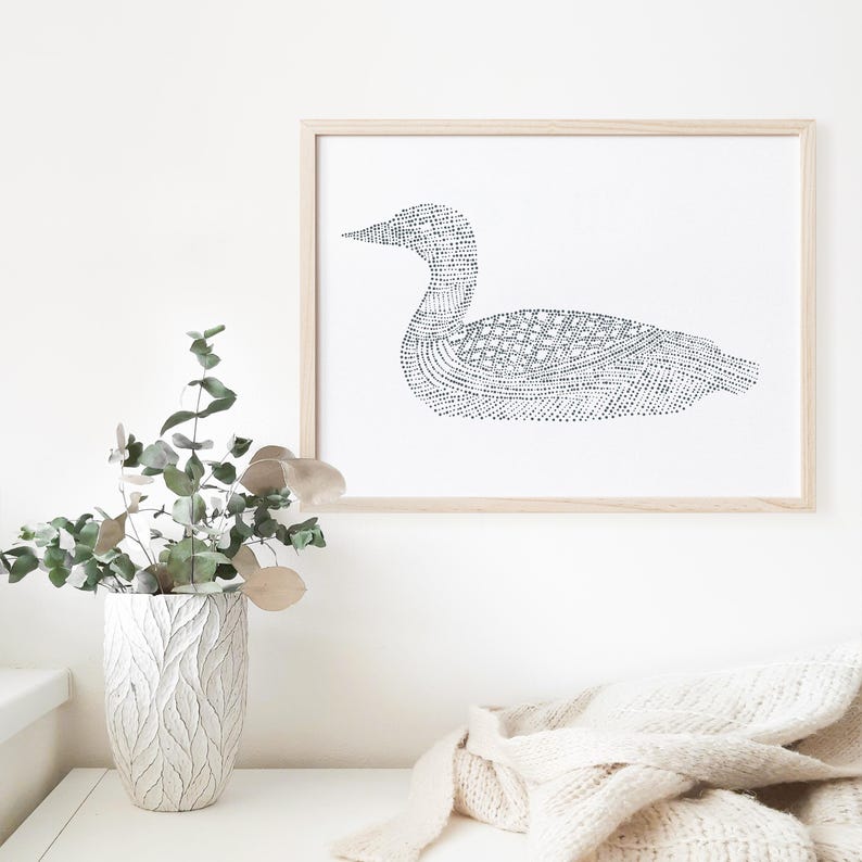 Puede incluir: Una impresi&oacute;n en blanco y negro de un p&aacute;jaro loon en l&iacute;nea de arte en un marco de madera simple. El loon est&aacute; hecho de peque&ntilde;os puntos y l&iacute;neas, creando un dise&ntilde;o detallado e intrincado.