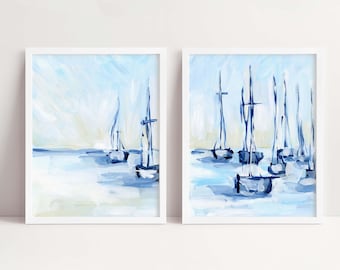 May include: Two framed paintings of abstract blue sailboats on a light blue background. The sailboats are painted in a loose, impressionistic style.