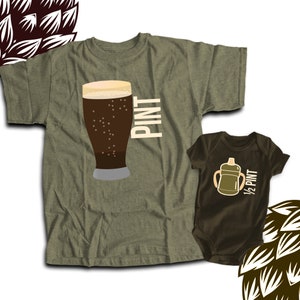 May include: Olive green t-shirt with a graphic of a pint of beer and the word "PINT" in white. A matching brown baby onesie features a cartoon bottle and the text "1/2 PINT".