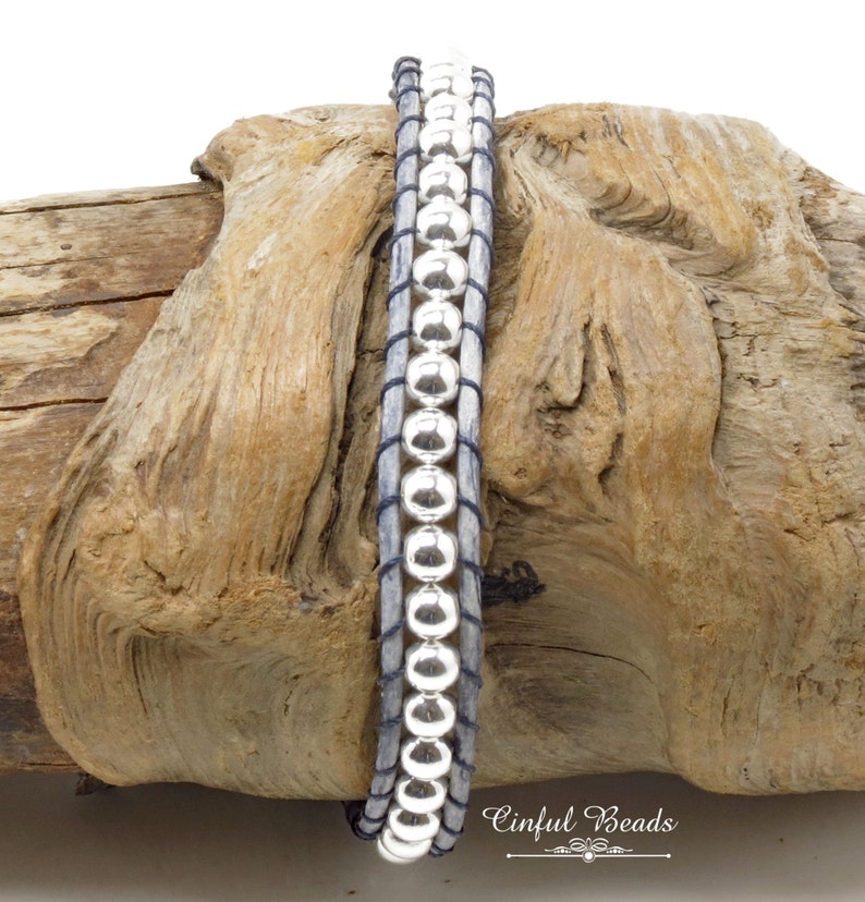 K&ouml;nnte beinhalten: Ein silbernes Perlenarmband mit einem grauen Lederband. Das Armband ist um ein St&uuml;ck Treibholz gewickelt. Der Text "Cinflul Beads" ist in der unteren rechten Ecke des Bildes sichtbar.