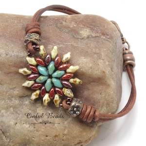 May include: A leather bracelet with a brown leather cord and a starburst-shaped bead cluster. The bead cluster is made of turquoise, red, and cream-colored beads. The bracelet has a metal clasp with a floral design. The text "Cinflful Beads" is visible below the bracelet.