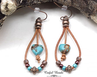 May include: A pair of turquoise and brown leather earrings with a heart-shaped turquoise bead and copper beads. The earrings are hanging from a wooden surface. "Cinfu Beads" is written on the bottom of the image.