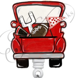 May include: Red pickup truck with a white tailgate filled with football game day items, including a football, a cheerleader's megaphone, and a pennant. The truck is attached to a white retractable badge reel.