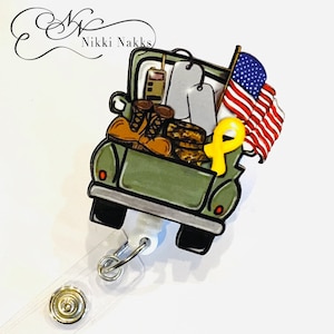 May include: A green toy truck with a yellow ribbon, a US flag, and military boots in the back. The truck is attached to a retractable badge holder.