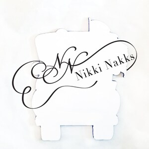 May include: White sticker with a black cursive script that says "Nikki Nakks" and a decorative flourish.