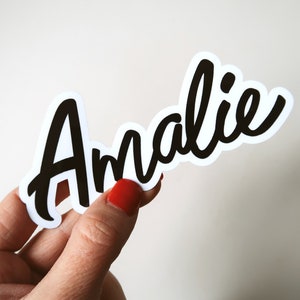 May include: A white sticker with the name "Amalie" written in black cursive lettering.