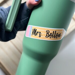 May include: Green travel mug with a pencil-shaped sticker that says "Mrs. Bolton".