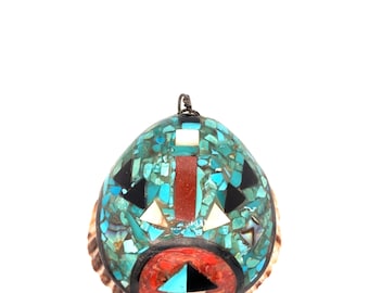 Puede incluir: Un colgante turquesa, negro, rojo y blanco con un diseño de mosaico. El colgante tiene forma de concha con un lazo de alambre en la parte superior. El mosaico presenta formas y patrones geométricos.