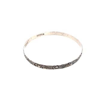 May include: A silver bangle bracelet with an intricate floral design. The bracelet is marked "STERLING" on the inside.