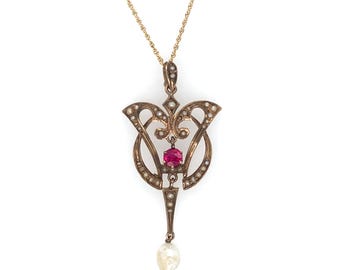 May include: A gold-toned pendant necklace featuring an ornate design with a central red gemstone and a dangling pearl. The pendant is adorned with small, white pearls and intricate metalwork, suspended from a delicate gold chain.