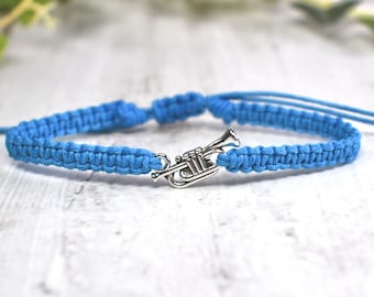 May include: A blue braided bracelet with a silver trumpet charm.