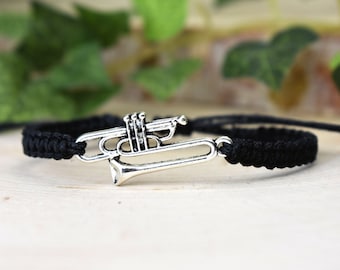 May include: A black braided bracelet with a silver trumpet charm.