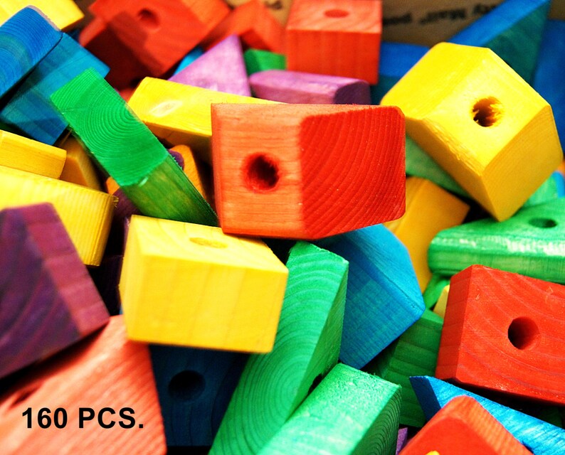 Puede incluir: Una gran pila de bloques de madera de colores, algunos con agujeros en el centro. Los bloques son de varias formas, incluyendo cuadrados, rect&aacute;ngulos y tri&aacute;ngulos. El texto "160 PCS." es visible en la esquina inferior izquierda de la imagen.
