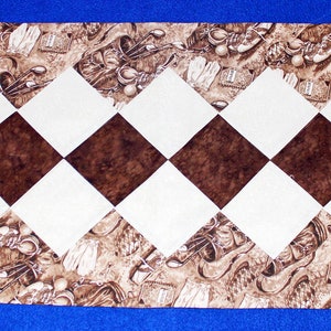 May include: A brown and white table runner with a checkered pattern. The runner has a brown border with a repeating pattern of golf clubs and golf balls.