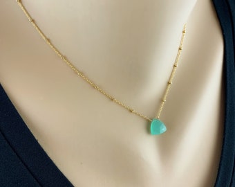 May include: A gold chain necklace with a light green heart-shaped pendant.