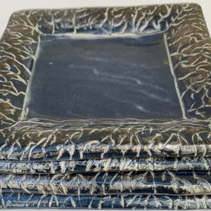 May include: Stack of four square ceramic plates with a dark blue glaze and a white crackle glaze design around the edges.