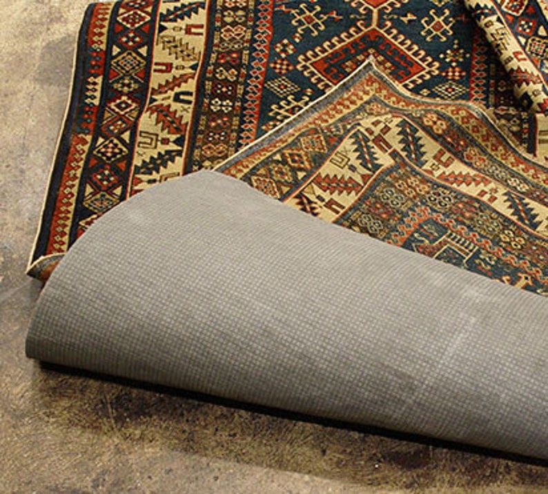 May include: A patterned rug with a dark blue background and intricate designs in red, yellow, and white. The rug is folded over a gray rug pad.
