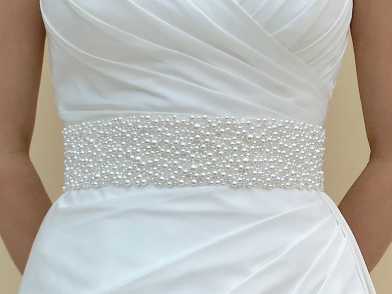 May include: A white satin wedding dress with a pearl beaded belt.