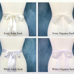 May include: Four white sashes, two made of satin and two made of organza. The sashes are tied in a bow around a white dress form. The sashes are labeled "Ivory Satin Sash", "Ivory Organza Sash", "White Satin Sash", and "White Organza Sash".