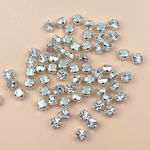 May include: A large pile of silver-toned sew-on rhinestones with clear crystal centres.