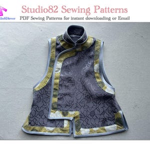 Puede incluir: Un chaleco gris sin mangas con cuello mandarín y estampado floral. El chaleco tiene ribetes amarillos y blancos alrededor de los bordes y un panel de tela gris contrastante en la parte delantera.