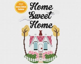 May include: Cross stitch pattern PDF for a home sweet home design. The pattern features a cute house with pink and white details, two trees, and a white picket fence. The text "Home Sweet Home" is written in black above the house.