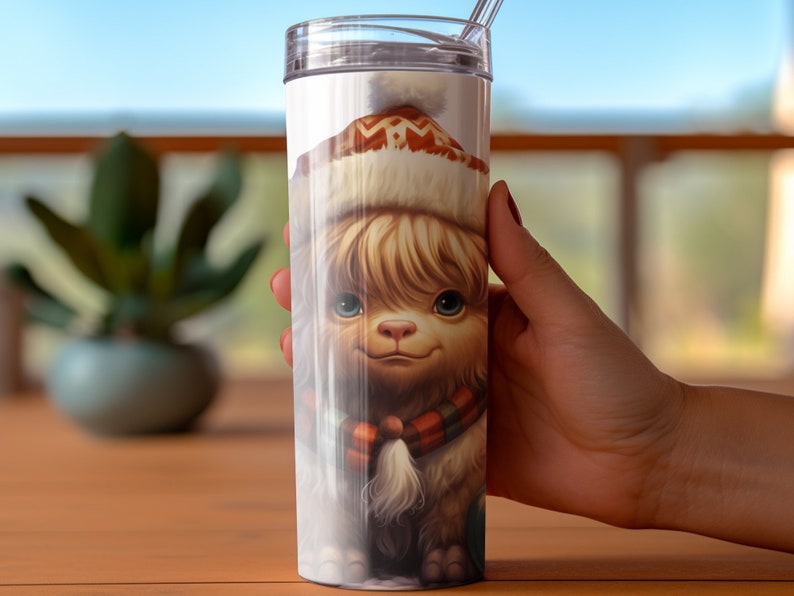 May include: A 20-ounce stainless steel tumbler features a whimsical illustration of a fluffy, light brown creature wearing a warm, patterned winter hat and a red and orange scarf. The creature's eyes are large and expressive, and its overall appearance is cute and endearing. The tumbler is white and has a clear lid with a straw.  The image is high-quality and detailed, showcasing the creature's soft fur and the intricate design of its hat and scarf.